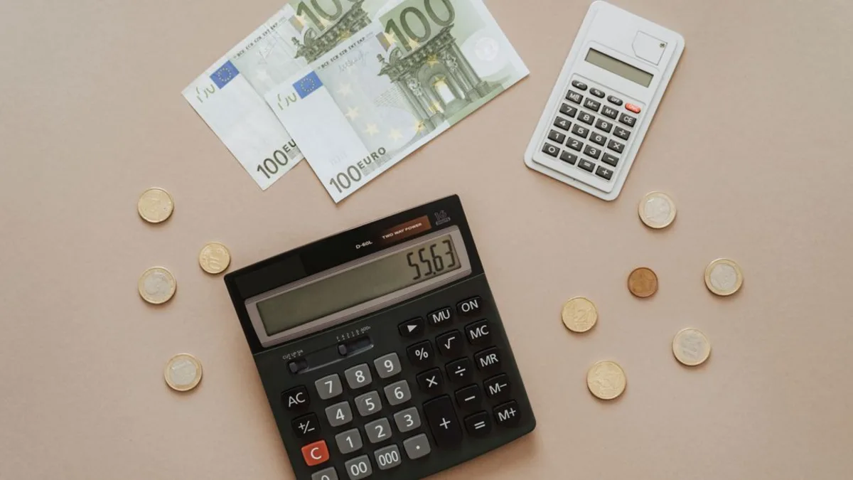Calcolatrice, banconote in euro e documenti fiscali su una scrivania