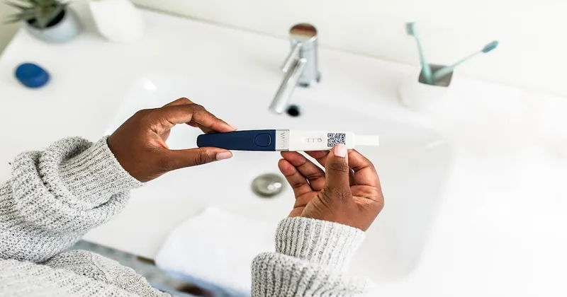Mani che tengono un test di ovulazione sopra il lavandino del bagno, per individuare il periodo fertile