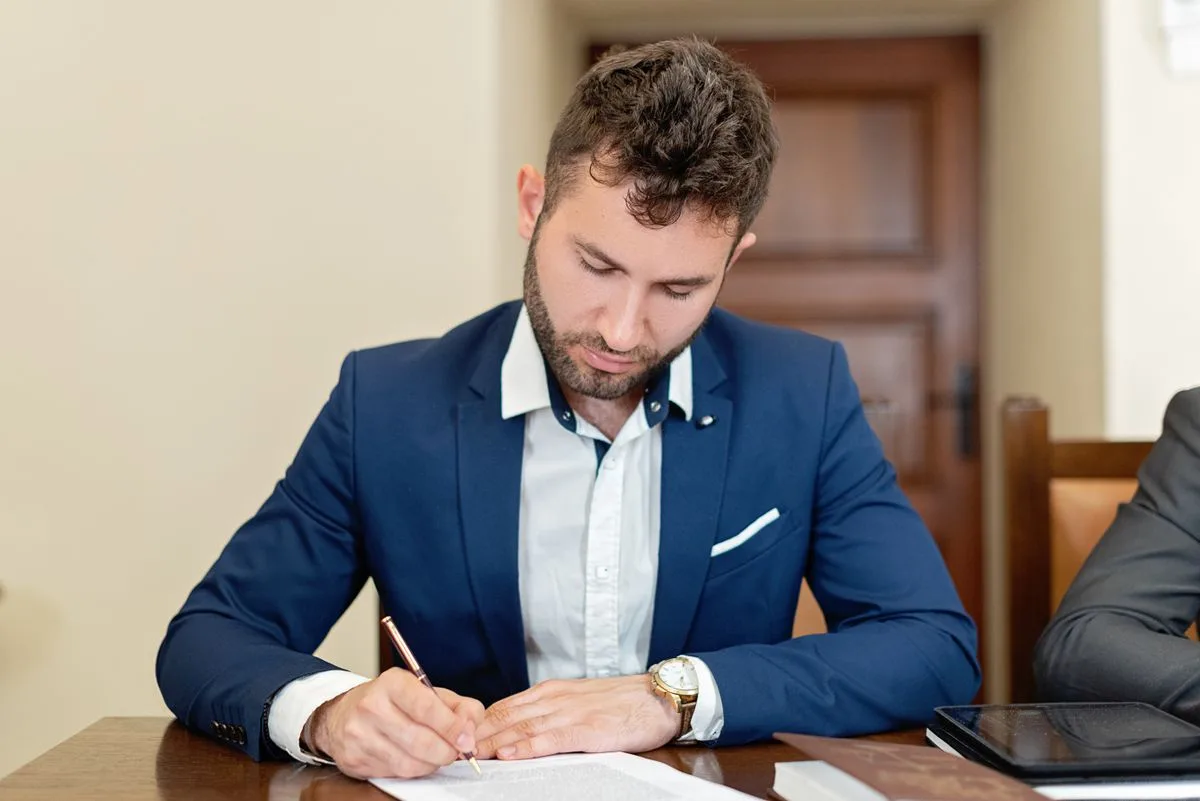 Professionista in giacca che firma un contratto alla scrivania