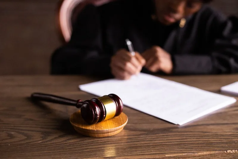 Martelletto del giudice e mani che firmano un atto legale