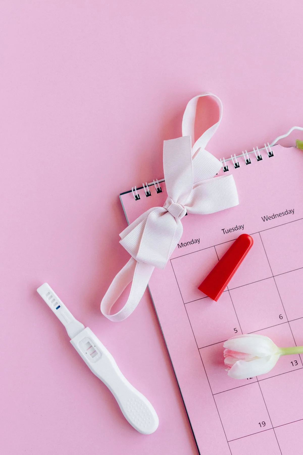 Kit per test di gravidanza e calendario su fondo rosa